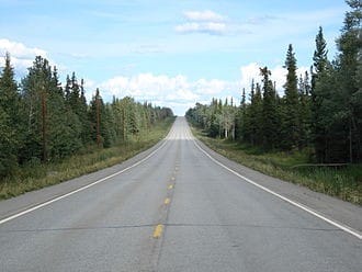 Photo of long desolate straight road boardered by spruce forests to the horizon